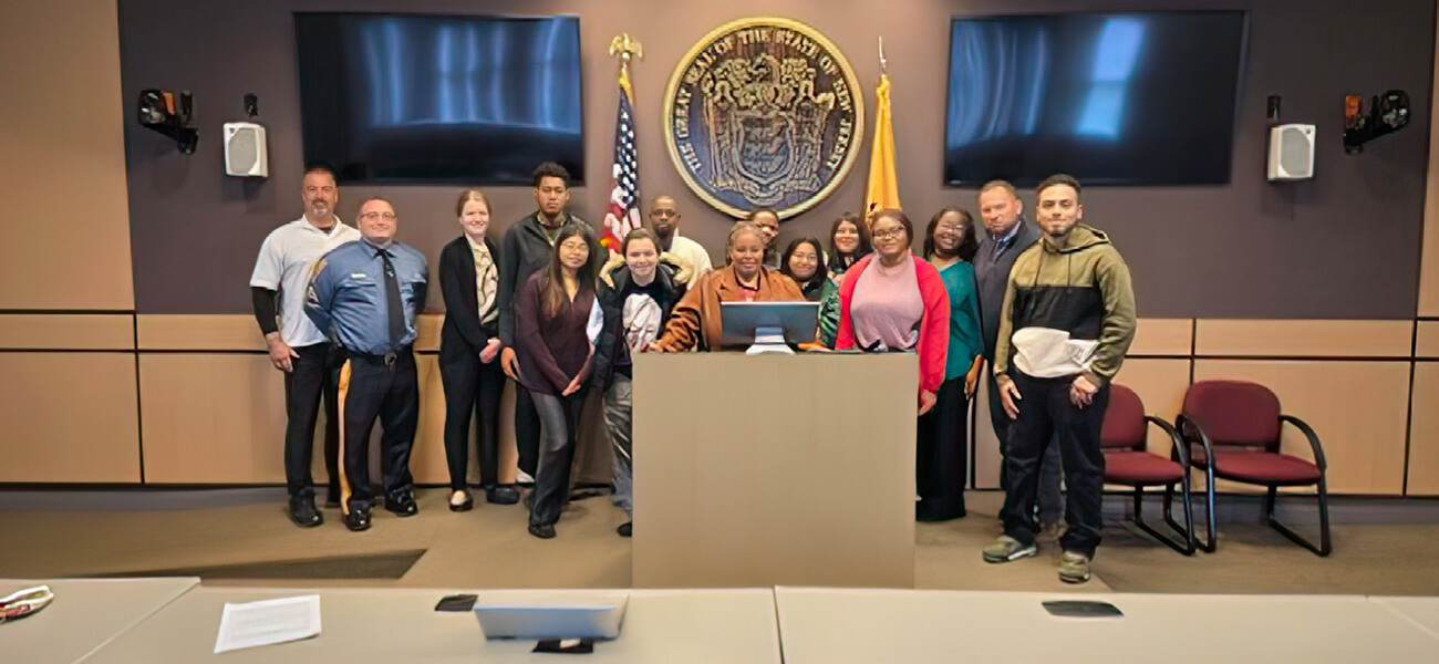 A diverse group of people stands together in front of a podium, engaged in conversation or awaiting a presentation