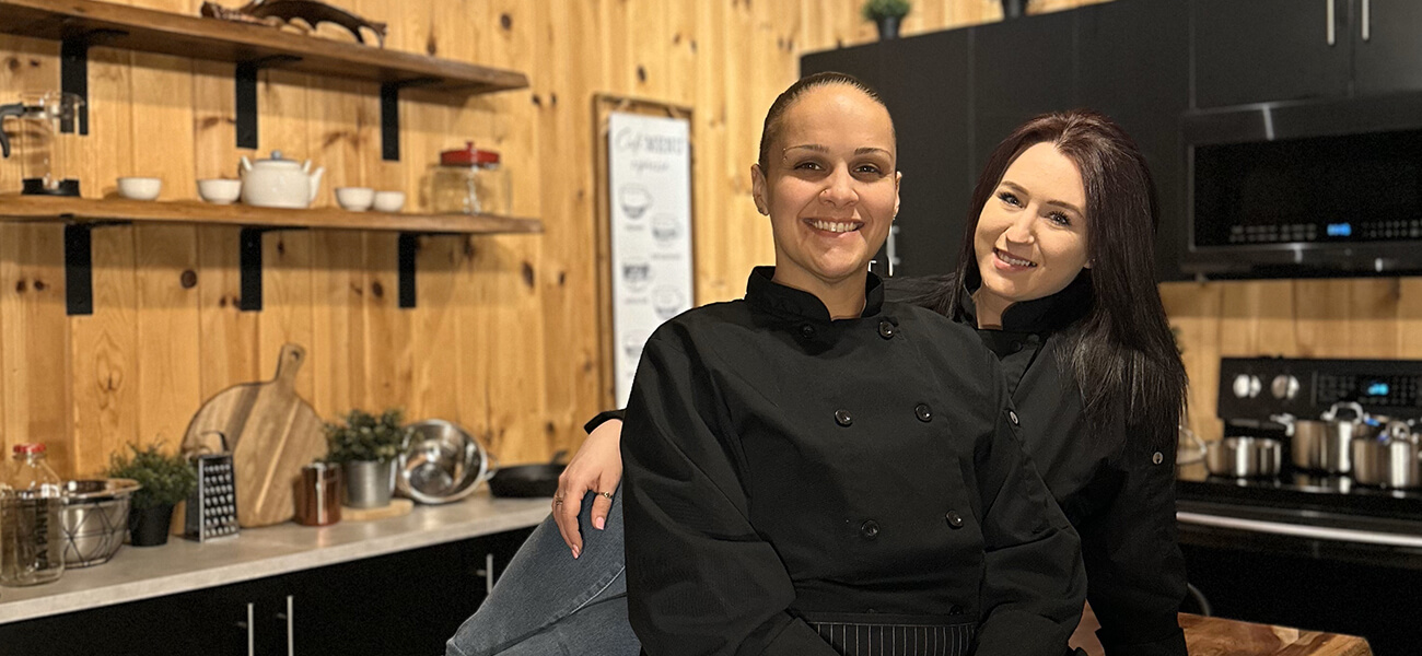 Two women engaged in conversation while seated at a wooden table in a cozy kitchen setting